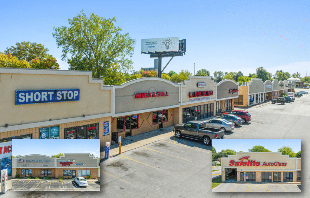 A strip mall with various stores and parked cars under a clear sky.
